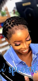 A smiling woman with braids in a blue denim shirt.