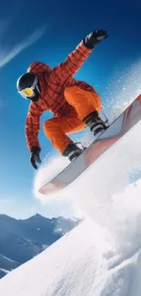 A snowboarder jumps over snowy peaks under a bright blue sky.