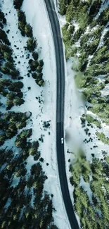 Aerial view of snowy forest with road.