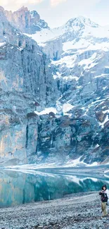 Snowy mountain landscape with lake reflection and hiker.