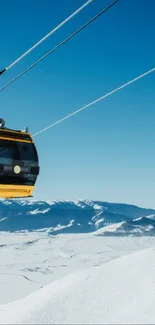 Cable car over snowy mountains with blue sky.