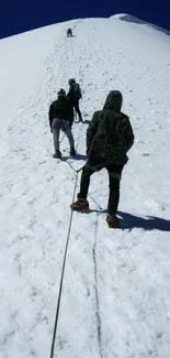 Climbers ascend a snowy mountain under a deep blue sky.