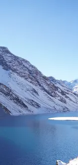 Snowy mountain landscape with blue lake and clear sky.