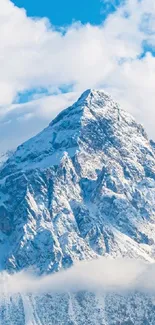 Snowy mountain peak under blue sky with fluffy clouds.