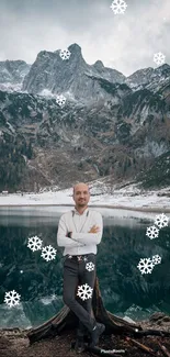 Man standing by mountain lake with snowflakes falling.