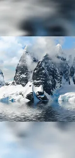 Snow-covered mountains reflecting in calm water under a cloudy sky.