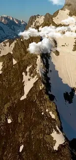 Aerial view of rocky mountain peaks covered in snow under a clear blue sky.