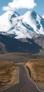 Snowy mountain landscape with road and blue sky.