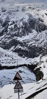 Snowy mountain road with warning signs in winter landscape.