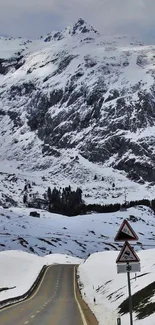 Snowy mountain road with scenic views and towering peaks.