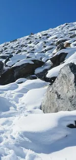 Snowy mountain landscape with rocks and blue sky.