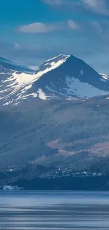 Majestic snowy mountain with serene water reflection and lush greenery.