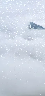 Mobile wallpaper of a snowy mountain peak with clouds and falling snowflakes.