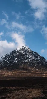 Snowy mountain under a blue sky with clouds.