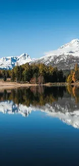 Snow-capped mountains reflecting in a calm lake with clear blue skies.