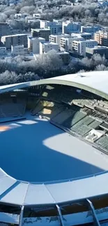 Aerial view of a snowy stadium in winter cityscape.