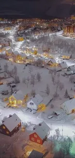 Aerial nighttime view of snowy town with glowing lights.