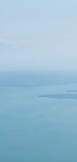 A lone bird flying over a calm, expansive sea beneath a serene sky.