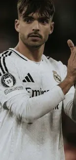 Soccer player in white jersey applauding on the field.