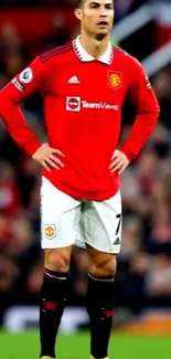 Soccer player in red jersey standing on a football field.