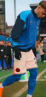 Soccer player in blue jacket preparing for match at the stadium.