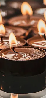 Warm candlelight with flickering flames creates a serene and calming mobile wallpaper.