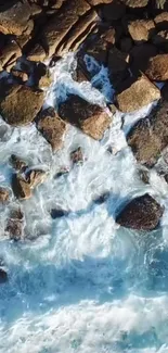 Aerial view of ocean waves crashing over rugged coastal rocks in blue hues.