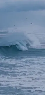 A calming ocean wave crashing under a cloudy blue sky.