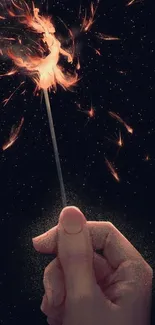 Hand holding sparkler with a starry night background.