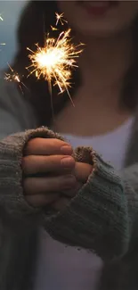 A sparkler illuminating cozy hands in knitted sleeves.