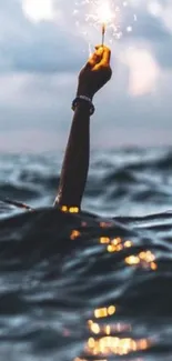 Hand holding a sparkler in dark ocean waves at night.