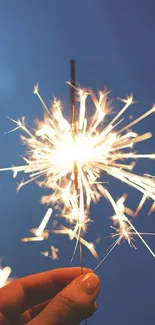 Vibrant sparkler glowing against a soft blue sky background.