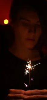 Person holding a sparkler in the dark, creating a magical glow.