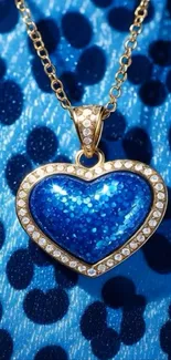 Blue heart pendant with gold chain on a textured background.
