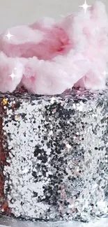 Glittery silver cake topped with pink cotton candy on a marble plate.