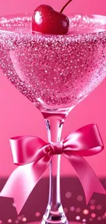 Sparkling cherry cocktail glass with pink ribbon on pink background.