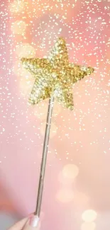 A sparkling gold star wand on a soft pink bokeh background.