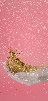 A hand tossing gold glitter on a pink background wallpaper.