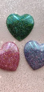 Three sparkling glitter hearts on blush background.