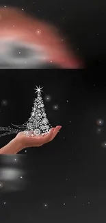 Hand holding a sparkling holiday tree against a dark starry sky.