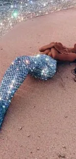 Mobile wallpaper with a sparkling mermaid on a sandy beach.