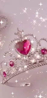 Pink crown and wand with sparkling jewels on a light background.