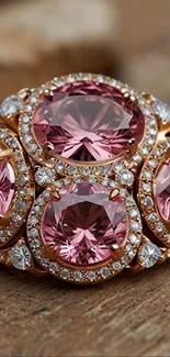 Sparkling pink gemstone ring with diamonds on a wooden surface.