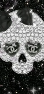 Sparkling skull with rhinestones and bow on black glittery background.