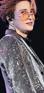 Sparkling stage performer with silver shimmering attire and stylish glasses.