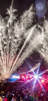 Spectacular fireworks display above a crowded festival at night.