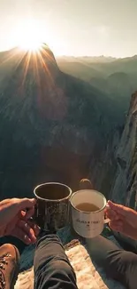 Two people enjoying sunrise over a mountain cliff with coffee cups.