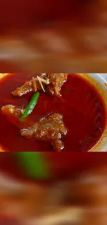 A vibrant red spicy curry in a white bowl.