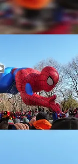 Spider-Man balloon floating over crowd in parade with blue sky.