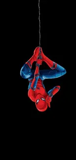 Spider-Man hanging upside down on black background mobile wallpaper.